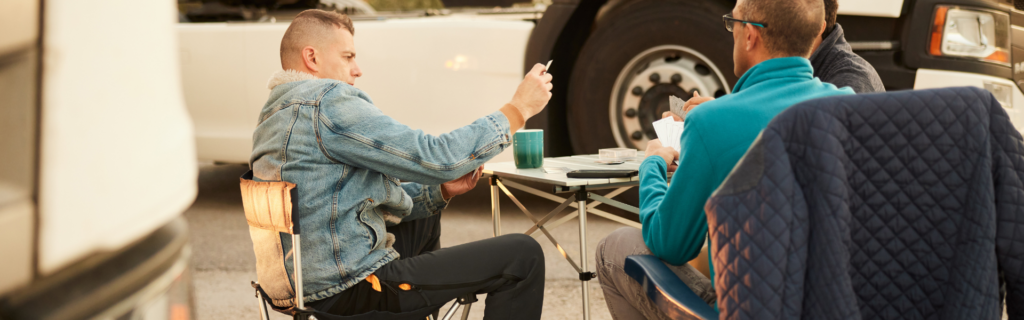 truckers sitting at folding table in truck stop parking lot