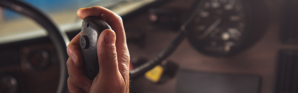 Hand holding cb radio inside cab of semi truck