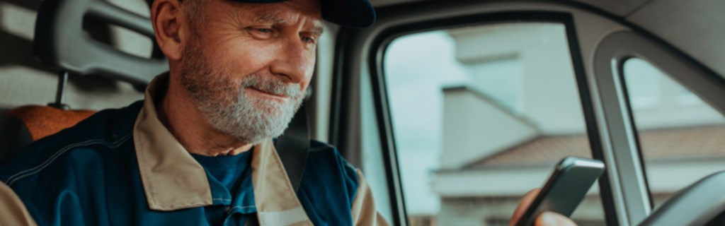 older trucker looking at phone in cab