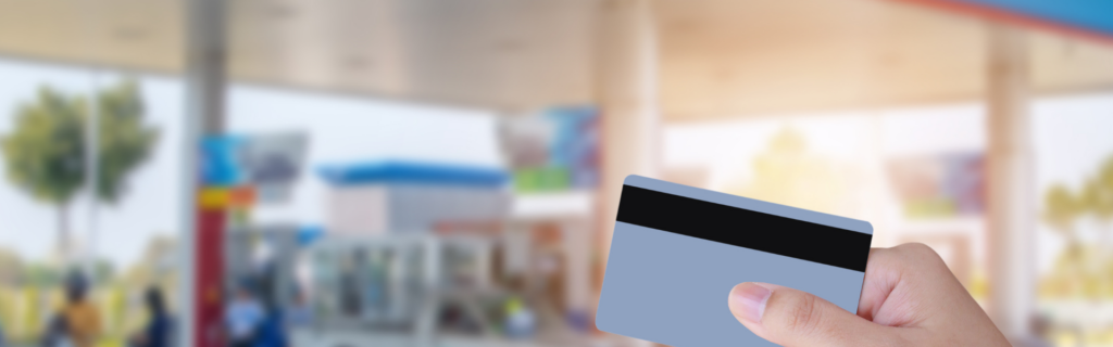 credit card in foreground and fuel pumps in background