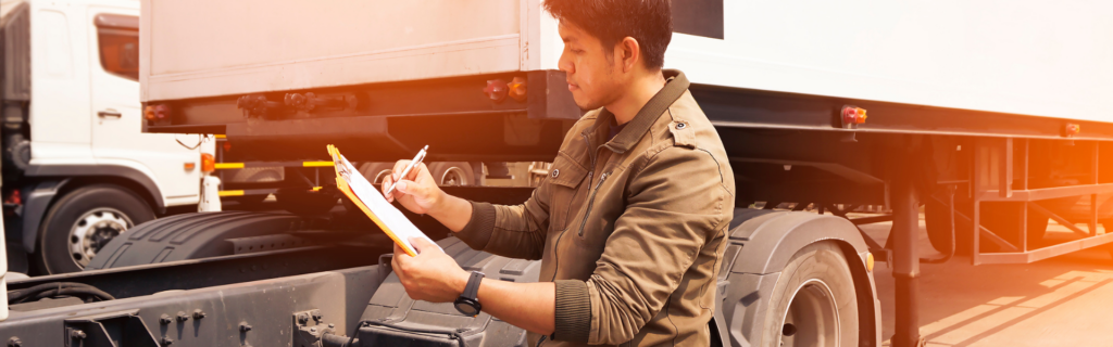 man with clip board looking at semi truck