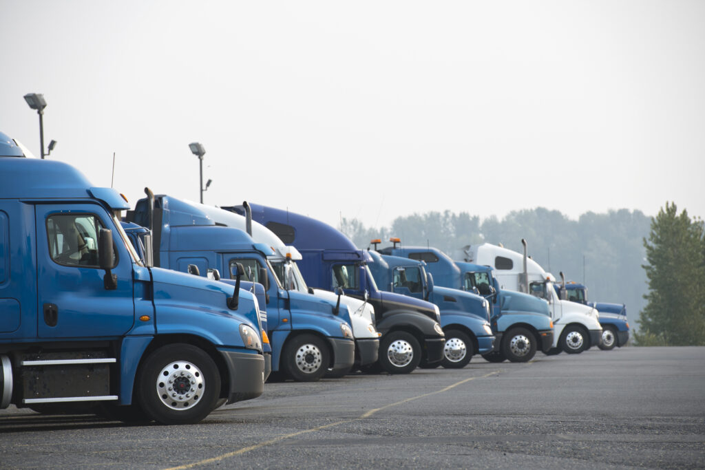 Profiles of different big rigs semi trucks standing in row on parking lot