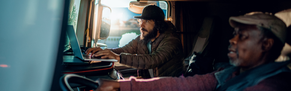black man and bearded man in semi truck cab
