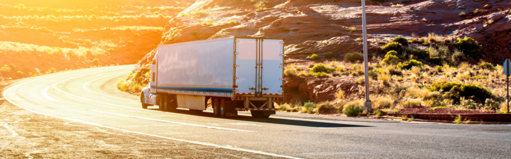 semi truck on curving road at sunset