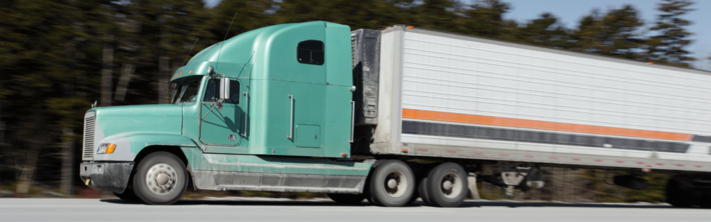 green truck pulling white trailer with orange and black stripes