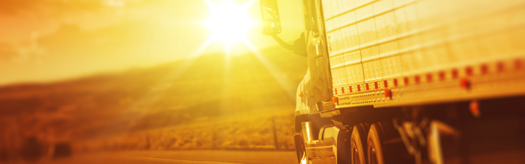 semi truck driving towards sunrise