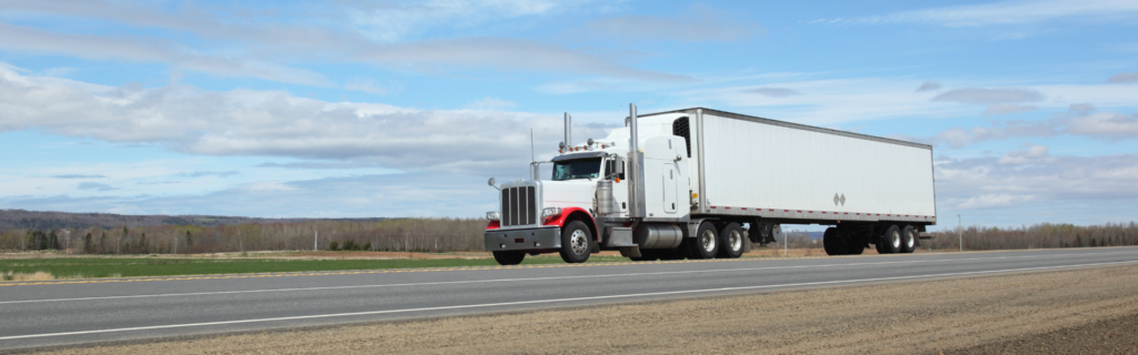 white semi truck pulling white trailer on road