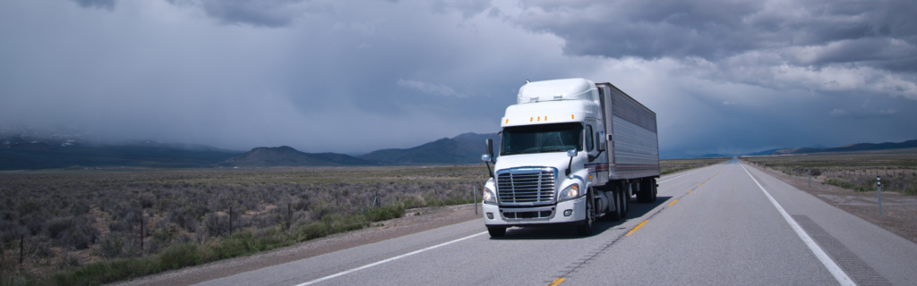 white semi truck on road with cloudy skies in the background