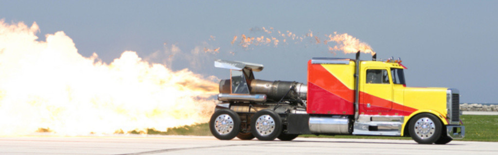 red and yellow semi truck drag racing with flames coming out the back and stacks