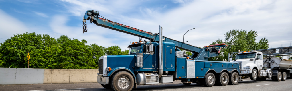 semi truck being towed by blue tow truck