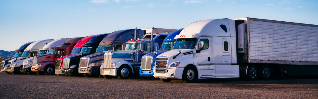 line of various types of semi trucks parked in a row