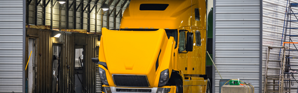 yellow semi truck in garage with hood up