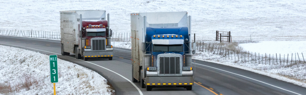 two semi trucks on snowy, curvy road