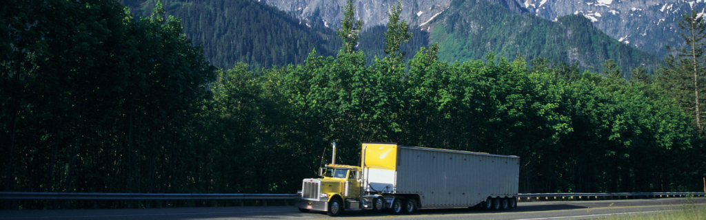 yellow semi truck navigating high elevation mountain road with forest and mountains in background, elevation and truck performance